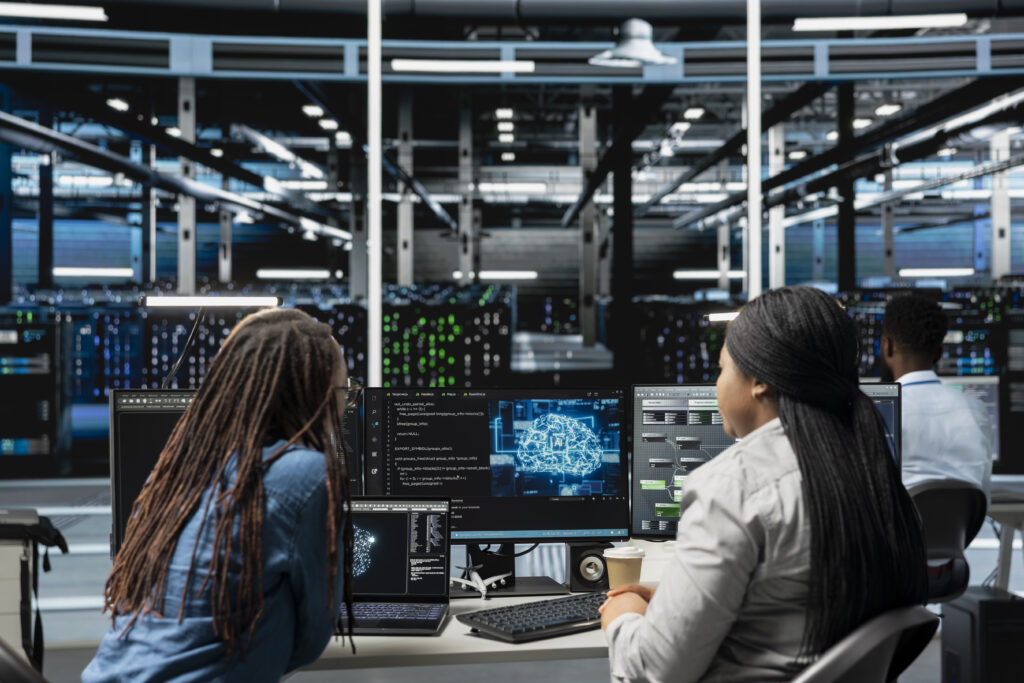 Data center engineering team working together, using AI visualization to oversee automated repetitive tasks. Server farm teamworking colleagues modifying systems based on data analytics graphs